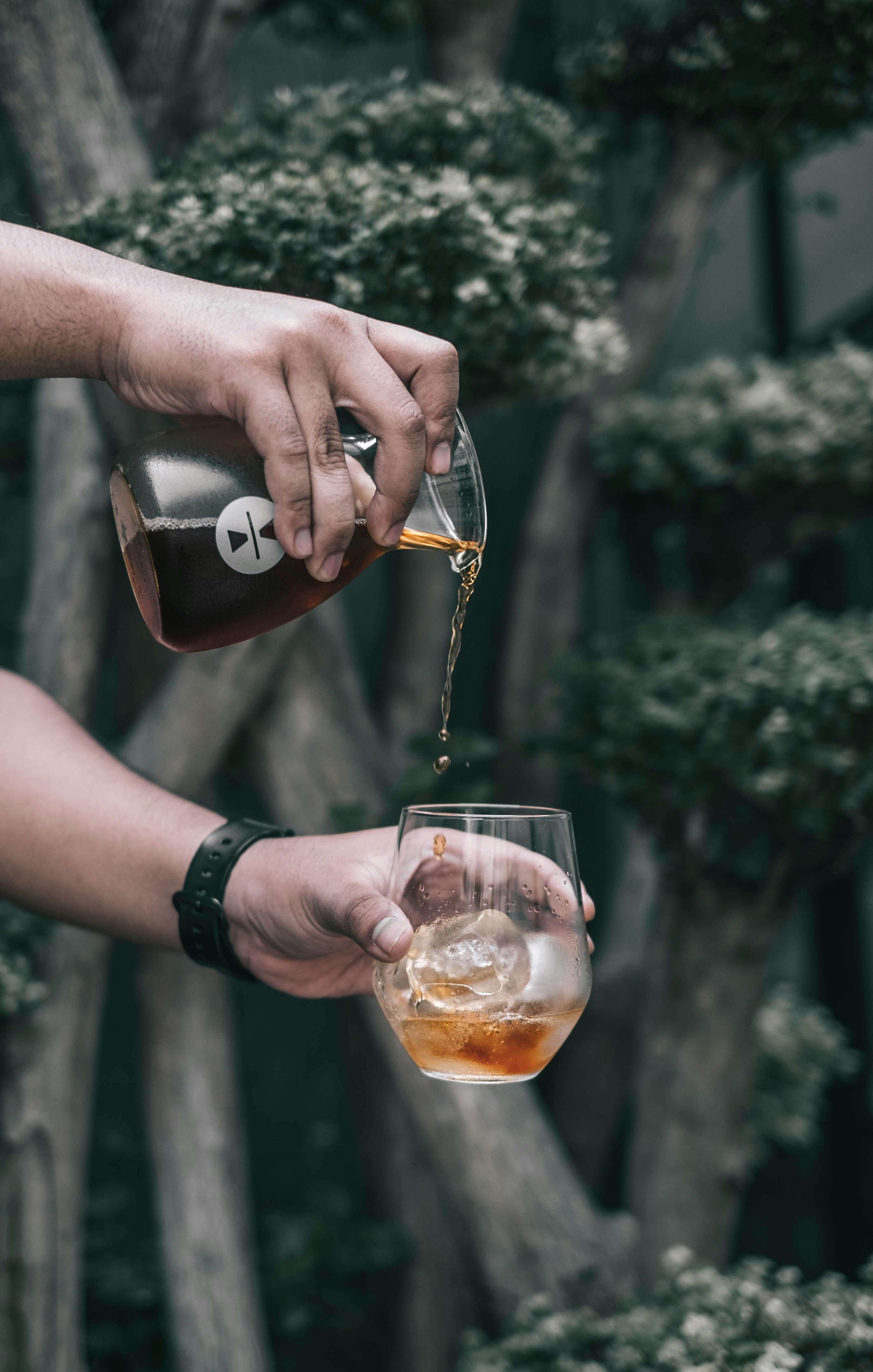 person pouring liquor in drinking glass